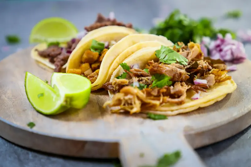 Tacos sobre una tabla de madera con limones
